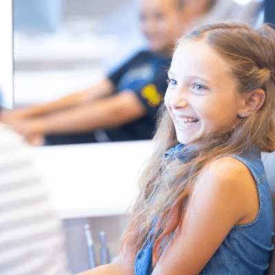 Little girl sitting and smiling at hentscher-johnson orthodontics, representing flexible orthodontic financing