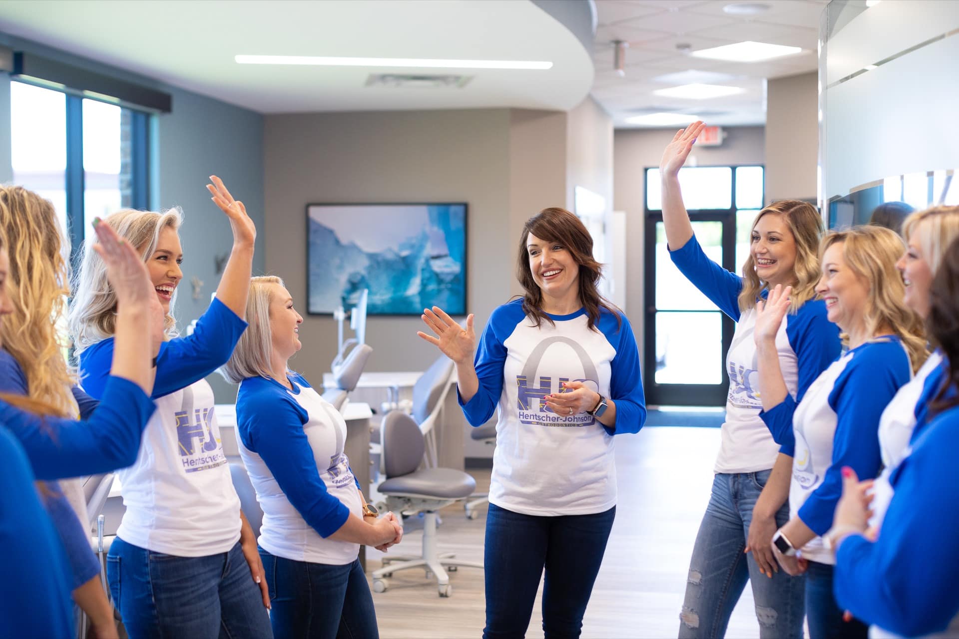 Hentscher-johnson orthodontics team celebrating together inside the office with high-fives and smiles.