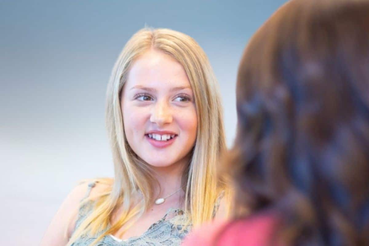 Blonde girl smiling before starting clear braces treatment.