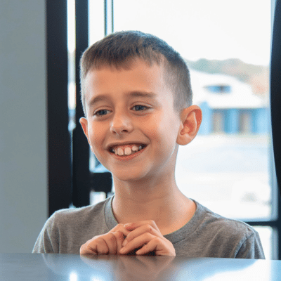 Smiling boy at the front desk at hentscher-johnson orthodontics, representing benefits of correcting bite problems