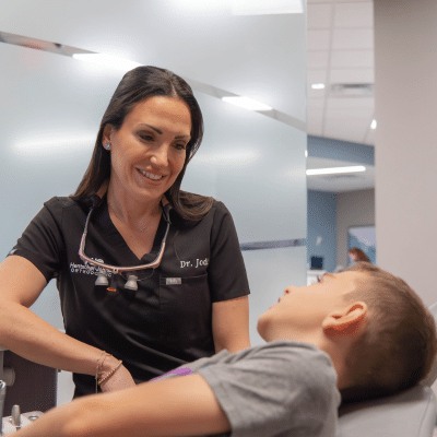 Dr. Jodi at hjo talks with a young boy about treatment, representing why age seven early orthodontic evaluations matter